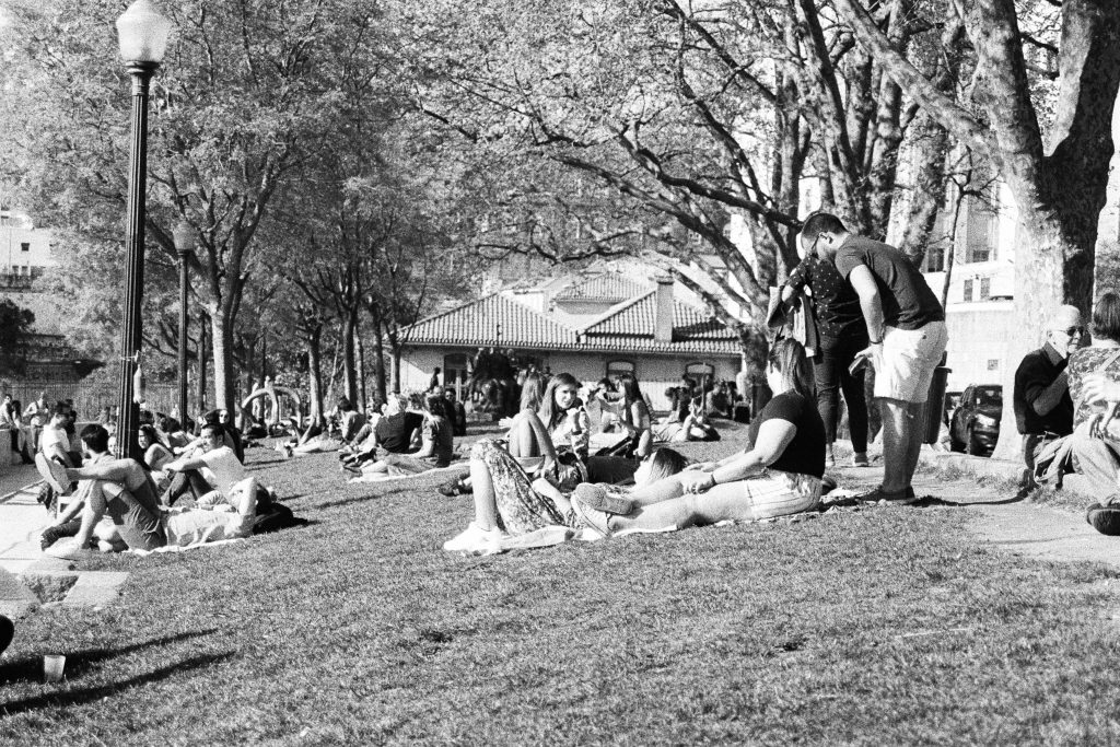 grayscale photo of people sitting on grass field
